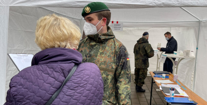Ein Soldat der Heimatschutzkompanie Bremen hilft einer Bremer Bürgerin beim Ausfüllen des Erfassungsbogens. Foto: Bundeswehr / Krey"