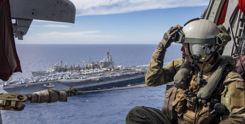 Chief Naval Aircrewman (Helicopter) Andrew Howard watches as the Nimitz-class aircraft carrier USS George H.W. Bush (CVN-77), sails alongside the supply-class fast combat support ship USNS Arctic (T-AOE-8) during a replenishment-at-sea, Sept. 29, 2022. US Navy Photo